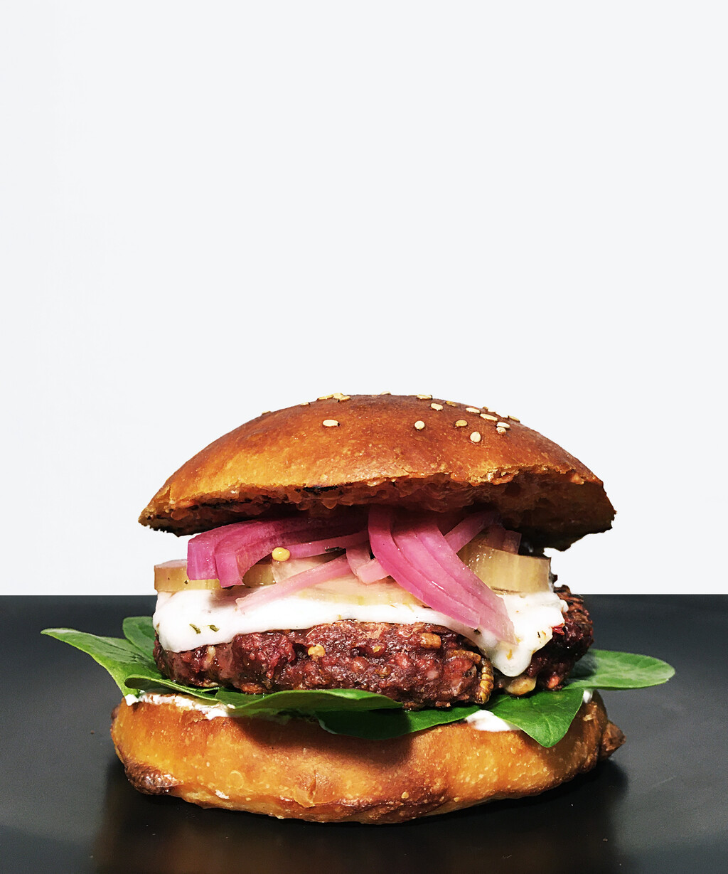 Sourdough bun; crème fraîche; baby spinach; beetroot, chick-pea and mealworm patty; goat cheese; quick-pickled cucumber and red onion; aji panca salsa.   